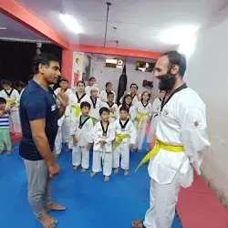 Children in white martial arts uniforms with yellow belts practicing in a dojo
