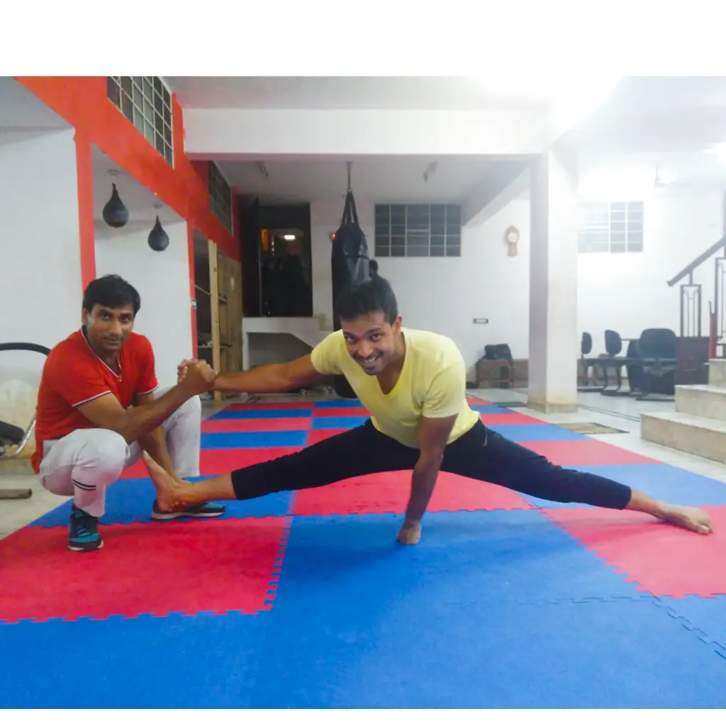 Two men practicing martial arts on red and blue mats in a studio